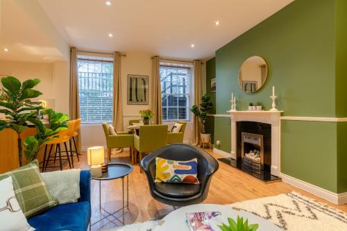sala de estar con paredes verdes y chimenea en Regency Basement Apartment en Cheltenham