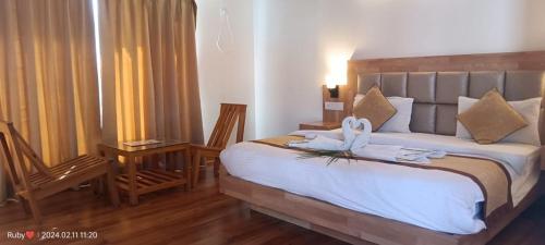 Jim Corbett Tiger Resort في Belparāo: غرفة نوم بسرير كبير عليها مناشف