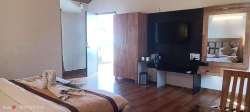 Dormitorio con cama, escritorio y TV en Jim Corbett Tiger Resort en Belparāo
