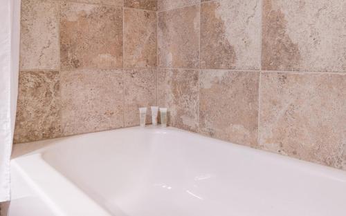 een wit bad in een betegelde badkamer bij The Hotel at La Valle in Rancho Santa Fe
