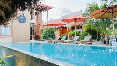 a swimming pool with lounge chairs and umbrellas at Canal Village Pakpra Phatthalung in Phatthalung