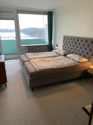 um quarto com uma cama grande e uma janela grande em Panoramablick über den See em Bad Segeberg