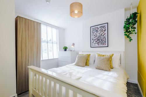 a white bedroom with a large bed with yellow pillows at Large 7 bedroom town house in Chester City Centre in Chester