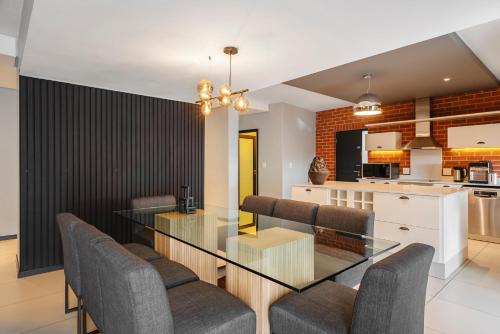 a dining room and kitchen with a glass table and chairs at CAG The Vantage Rosebank in Johannesburg