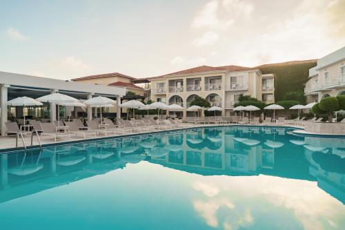 Diana Palace Hotel Zakynthos في أرغاسي: وجود مسبح في الفندق مع الكراسي والمظلات