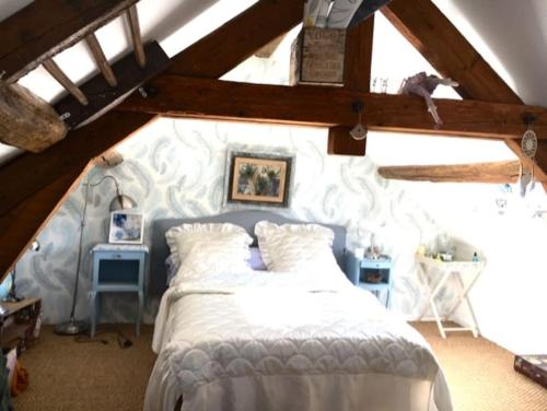 Cottage chaleureux face à l'étang في Précy: غرفة نوم بسرير أبيض في العلية