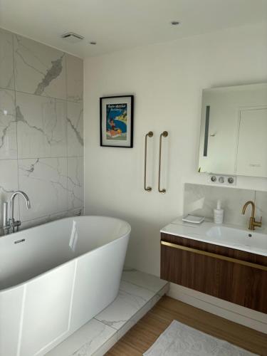 une salle de bain blanche avec une baignoire et un lavabo dans l'établissement La maison de Julia - Piscine privée, à Saint-Martin-des-Champs