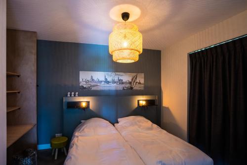 een slaapkamer met een groot bed en een kroonluchter bij Vakantiehuis aan het water met hottub in Dokkum