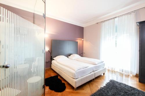 a bedroom with a bed and a glass door at Hotel Aurora in Merano
