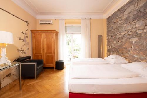 a hotel room with two beds and a stone wall at Hotel Aurora in Merano