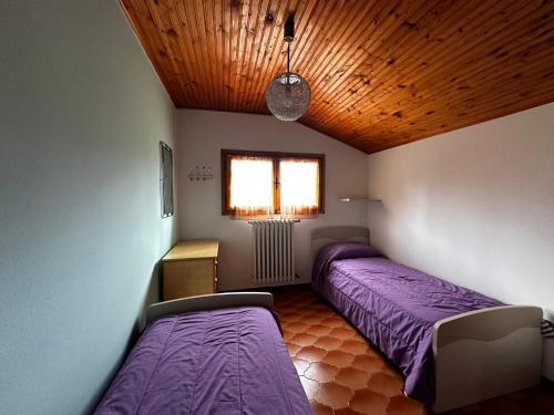 - 2 lits dans une chambre avec des draps violets dans l'établissement Appartamento Casa Vapi, à Pievepelago