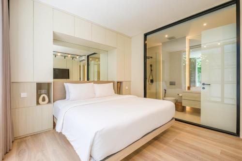 a bedroom with a large white bed and a bathroom at Oasis Smart Villa 3 Canggu in Canggu
