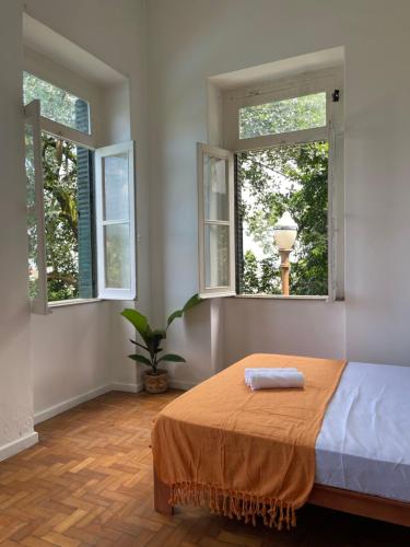 Castelo dos Tucanos Hostel في ريو دي جانيرو: غرفة نوم فيها نافذتين وسرير