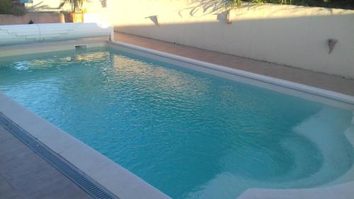 - une piscine d'eau bleue à côté d'un mur blanc dans l'établissement Aux Portes de la Camargue, à Arles