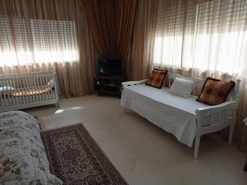 a bedroom with a bed and a tv and curtains at Chez Mme Jaouida in El Mourstane
