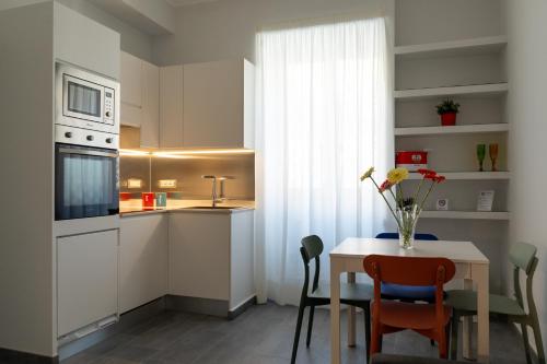 Damatti Appartamento في مسينة: مطبخ مع طاولة مع كراسي وميكروويف