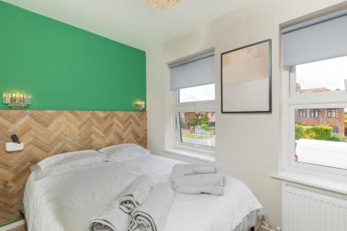 a bedroom with a white bed and two windows at Ocean Apartments in Littlehampton