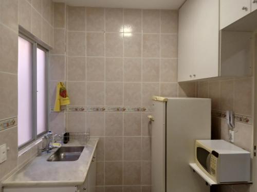 a kitchen with a sink and a refrigerator at Apartamento encantador in Belo Horizonte