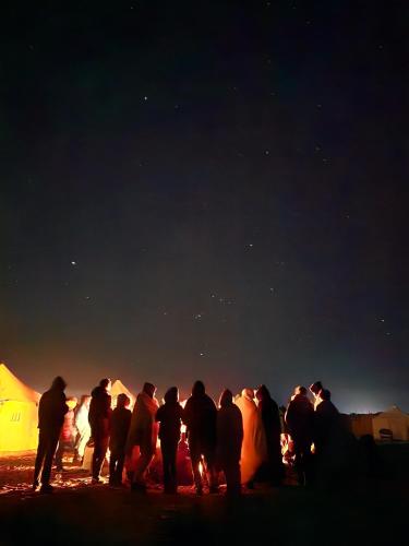 a group of people standing next to tents at night at flamingo camp in Dār as Salām