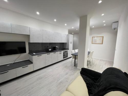 une grande cuisine avec des armoires blanches et une table dans l'établissement Saint Michel 3 piano, à Gorizia