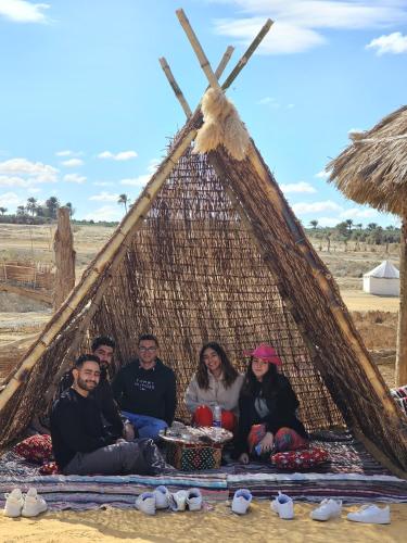 a group of people sitting in a straw hut at flamingo camp in Dār as Salām
