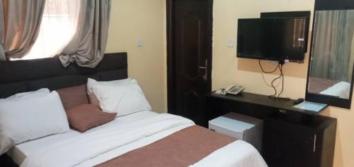 a hotel room with a bed and a television at Benji Apartments in Jiru