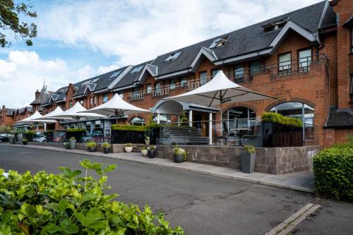 a building with white umbrellas in front of a street at Glynhill Hotel & Spa near Glasgow Airport in Paisley