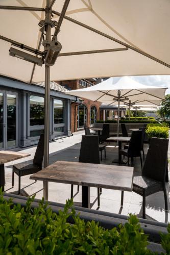 an outdoor patio with tables and chairs and umbrellas at Glynhill Hotel & Spa near Glasgow Airport in Paisley