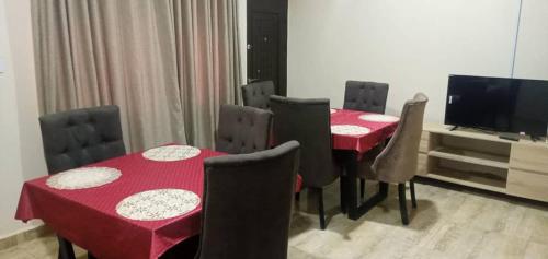 a dining room with red tables and chairs and a television at Benji Apartments in Jiru