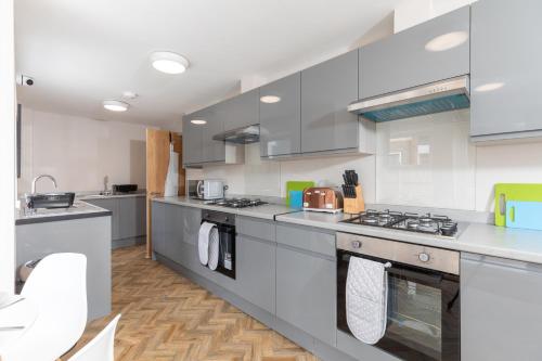 una cocina con electrodomésticos de acero inoxidable y armarios blancos en Ocean Apartments en Littlehampton