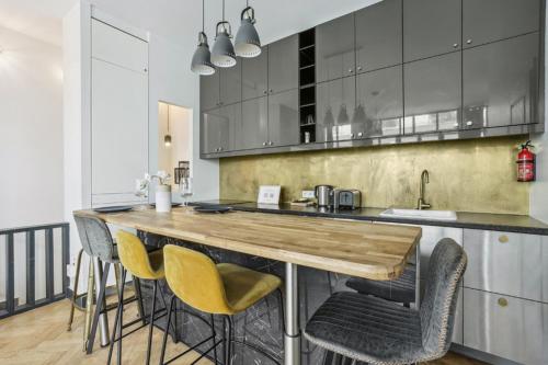 a kitchen with a wooden counter top and chairs at 142 Suite Ober - Superbe Appartement à Paris in Paris