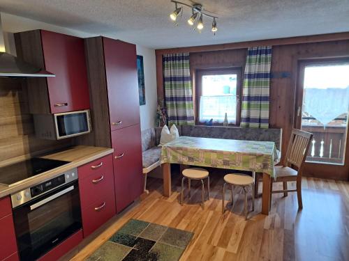 a kitchen with red cabinets and a table and chairs at Holiday Home Moosen - NKI210 by Interhome in Neukirchen am Großvenediger