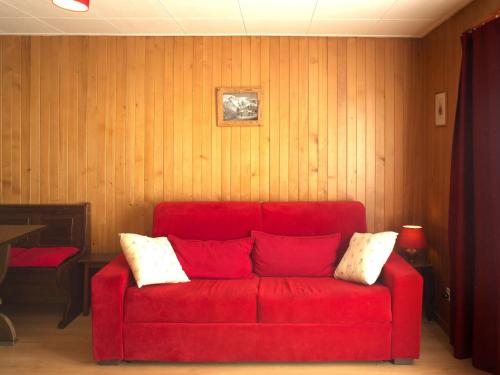 ein rotes Sofa in einem Zimmer mit Holzwänden in der Unterkunft Apartment Beausoleil 14 by Interhome in Verbier