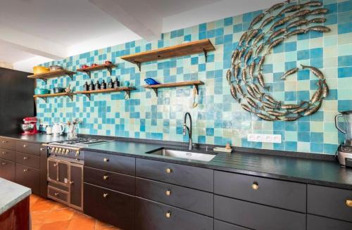 Il comprend une cuisine avec un évier et un mur carrelé bleu. dans l'établissement Grande maison en bord de rivière, à Cambes