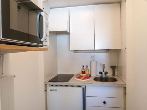 eine kleine Küche mit einer Spüle und einer Mikrowelle in der Unterkunft Apartment Rosablanche C65 by Interhome in Siviez