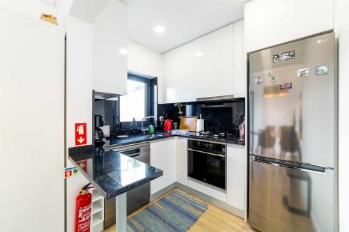 Una cocina con gabinetes blancos y un refrigerador de acero inoxidable. en MY HOME IS YOUR HOME Viana House, en Viana do Castelo