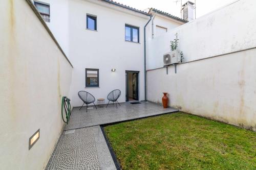 a courtyard of a white building with two chairs at MY HOME IS YOUR HOME – Viana House in Viana do Castelo