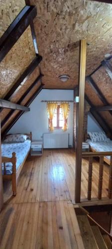 a attic room with two beds and two windows at Brvnara za odmor Tara in Bajina Bašta