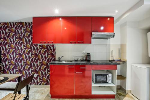 a kitchen with red cabinets and a microwave at 851 Suite Beautiful Superb Apartment in Asnières-sur-Seine