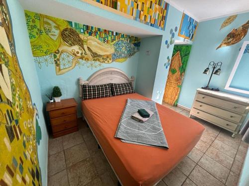 a bedroom with a bed with an orange bedspread at Hostel Los Duendes del Sur in Costa Del Silencio