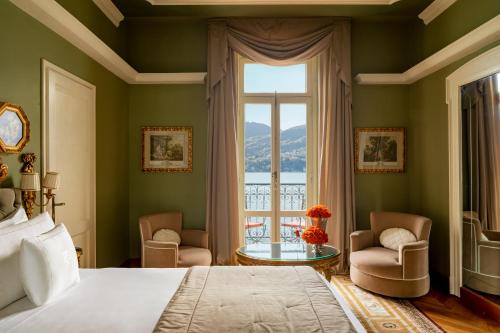 een slaapkamer met een bed, een raam en een tafel bij Grand Hotel Tremezzo in Tremezzo