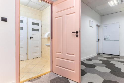 a bathroom with a pink door and a tile floor at Moon Hostel Warszawa in Warsaw