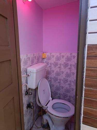 a bathroom with a toilet and a pink wall at gaurav home stay in Barkot