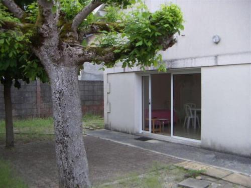 un arbre devant un bâtiment blanc avec une fenêtre dans l'établissement Appartement proche centre - P04202, à Soulac-sur-Mer