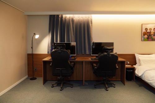 a bedroom with a desk with two chairs and a bed at Aank Hotel Suwon in Suwon