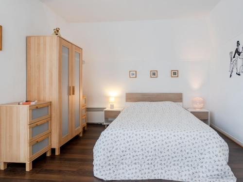 ブロンヴィル・シュル・メールにあるApartment Le Garden Fleuri by Interhomeのベッドルーム1室(ベッド1台付)、木製キャビネットが備わります。
