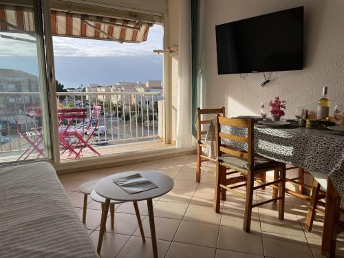 d'un salon avec une table et une vue sur un balcon. dans l'établissement Apartment Les Saladelles-4 by Interhome, au Grau-du-Roi