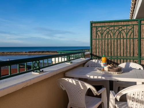 een balkon met een tafel en stoelen en de oceaan bij Apartment La Presqu'île-7 by Interhome in Cabourg