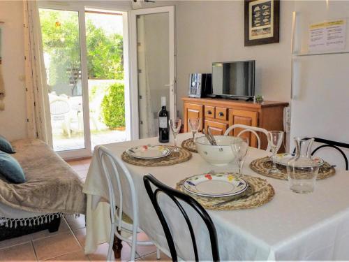 einen Esstisch mit einem weißen Tischtuch und Stühlen in der Unterkunft Holiday Home Les Jardins de la Clape by Interhome in Narbonne-Plage