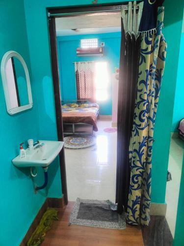 uma casa de banho com um lavatório e um espelho e um quarto em jharana guest house em Puri